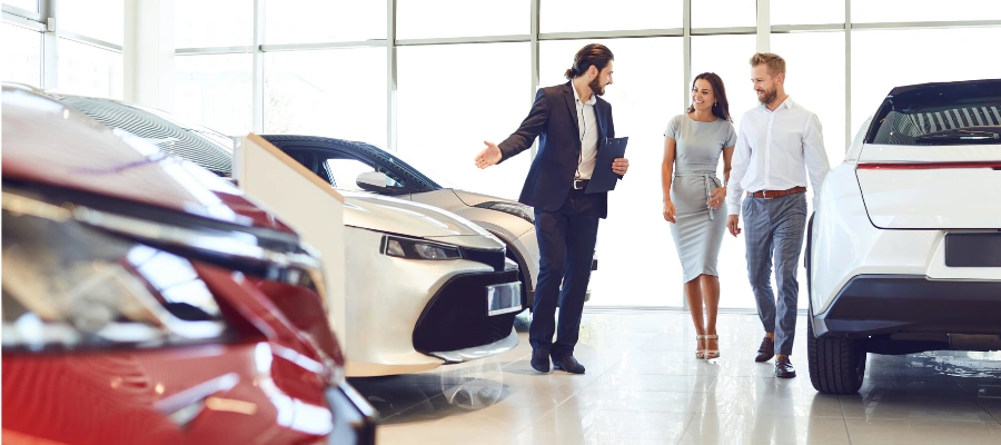 car salesman showing clients cars on the showroom floor
