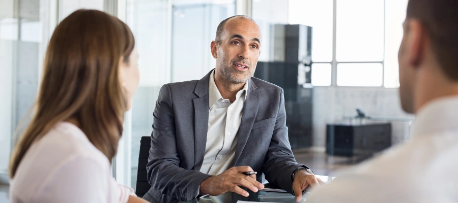 front of businessman meeting with man and woman seen from back