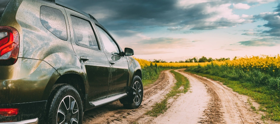 car on dirt road in field