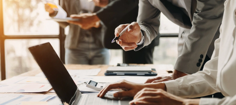 Business professionals working in an office with a laptop and paper documents.